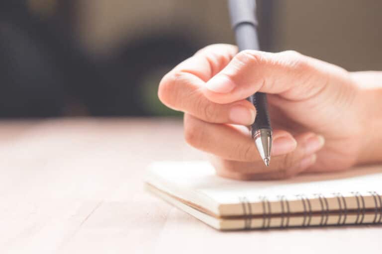 Business women hands working writing notebook on wooden desk, lighting effect