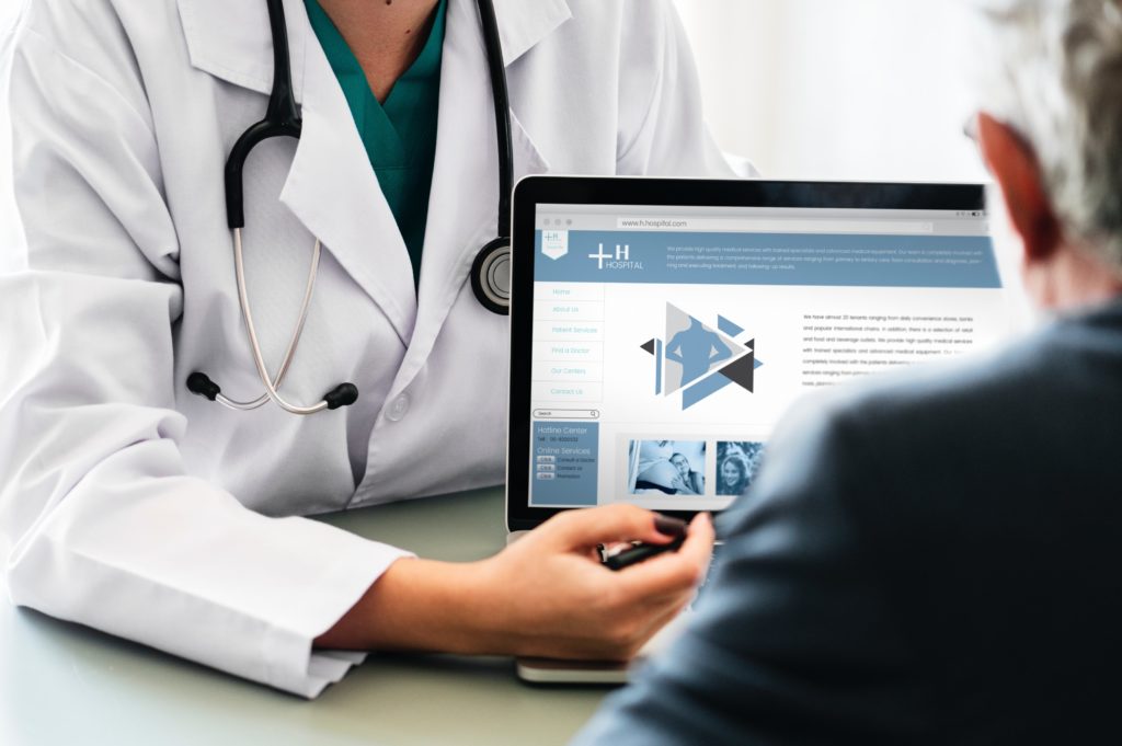 doctor pointing at laptop to patient