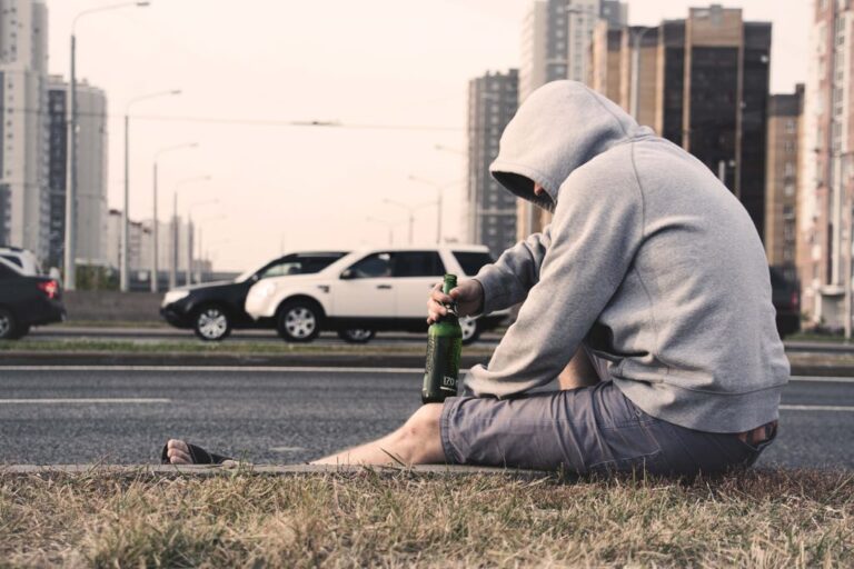 man drinking beer on curb