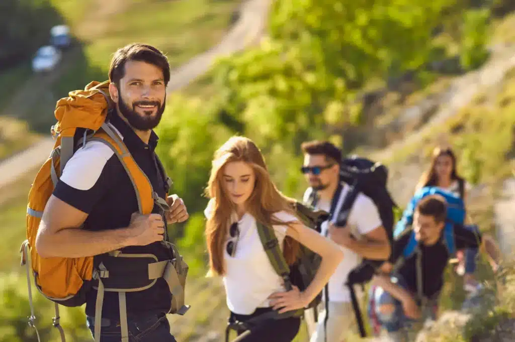 Man doing a common summer activity and hiking up a hill with friends,